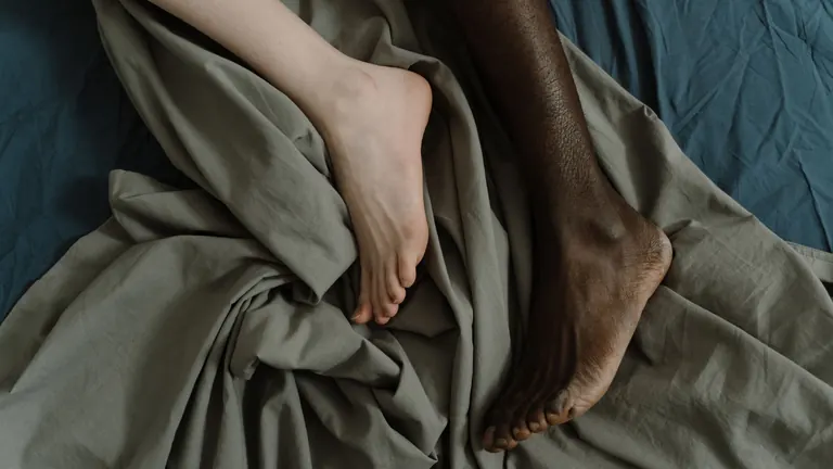 Nohy páru pod bílou přikrývkou – rimming a intimita v páru