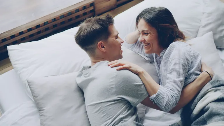 Pár se směje v posteli a vybírá erotické hračky pro páry